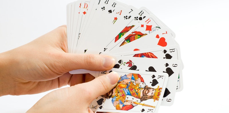 a person holding playing cards for tongits gameplay